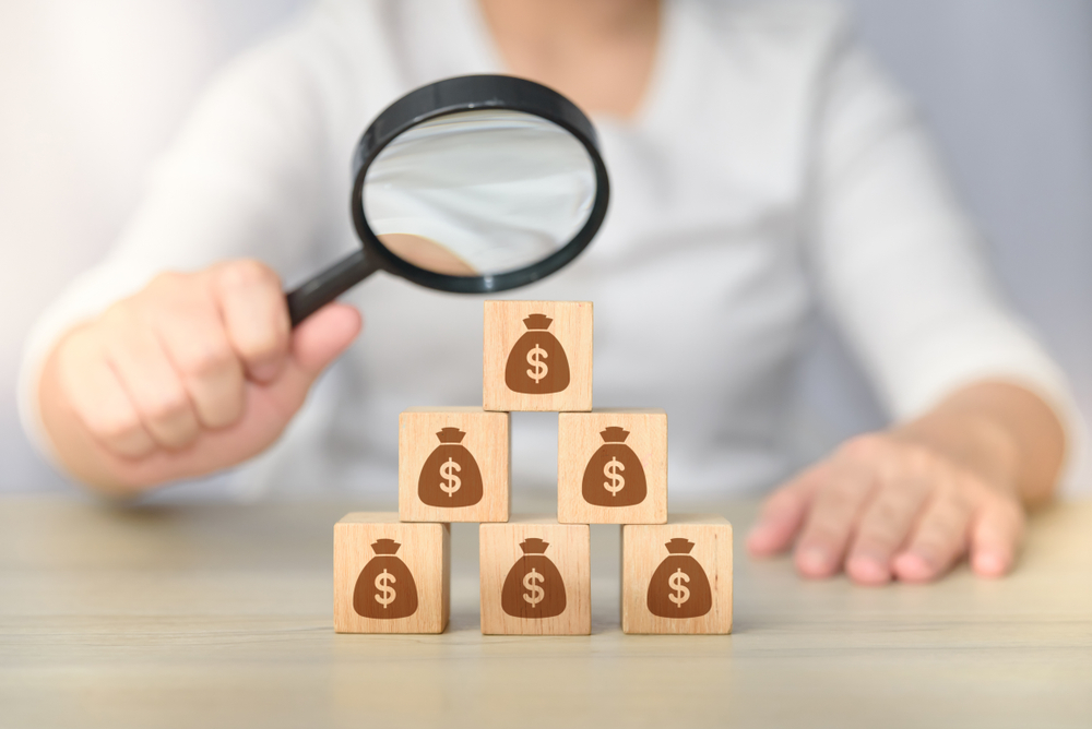 Search,For,Money,Magnifying,Glass,Investigating,Wooden,Block